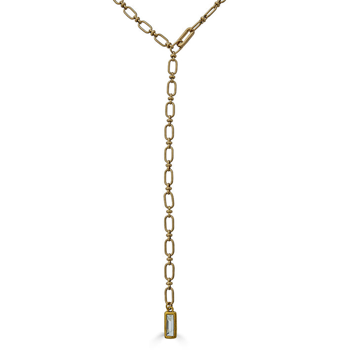 A matte gold lariat with crystal pendant