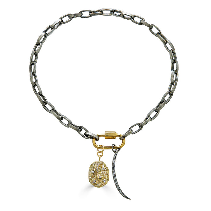A thick silver paperclip necklace with a gold carabiner and moon and star charms.
