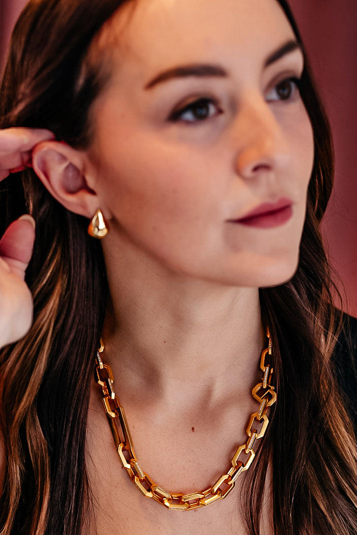 A model wearing A pair of gold teardrop earrings.