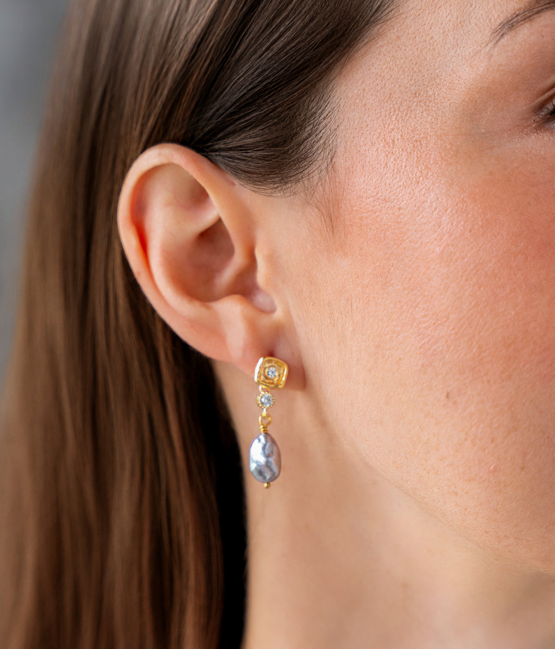 Gold drop earrings with iridescent gray keshi pearl drops and crystal accent details.