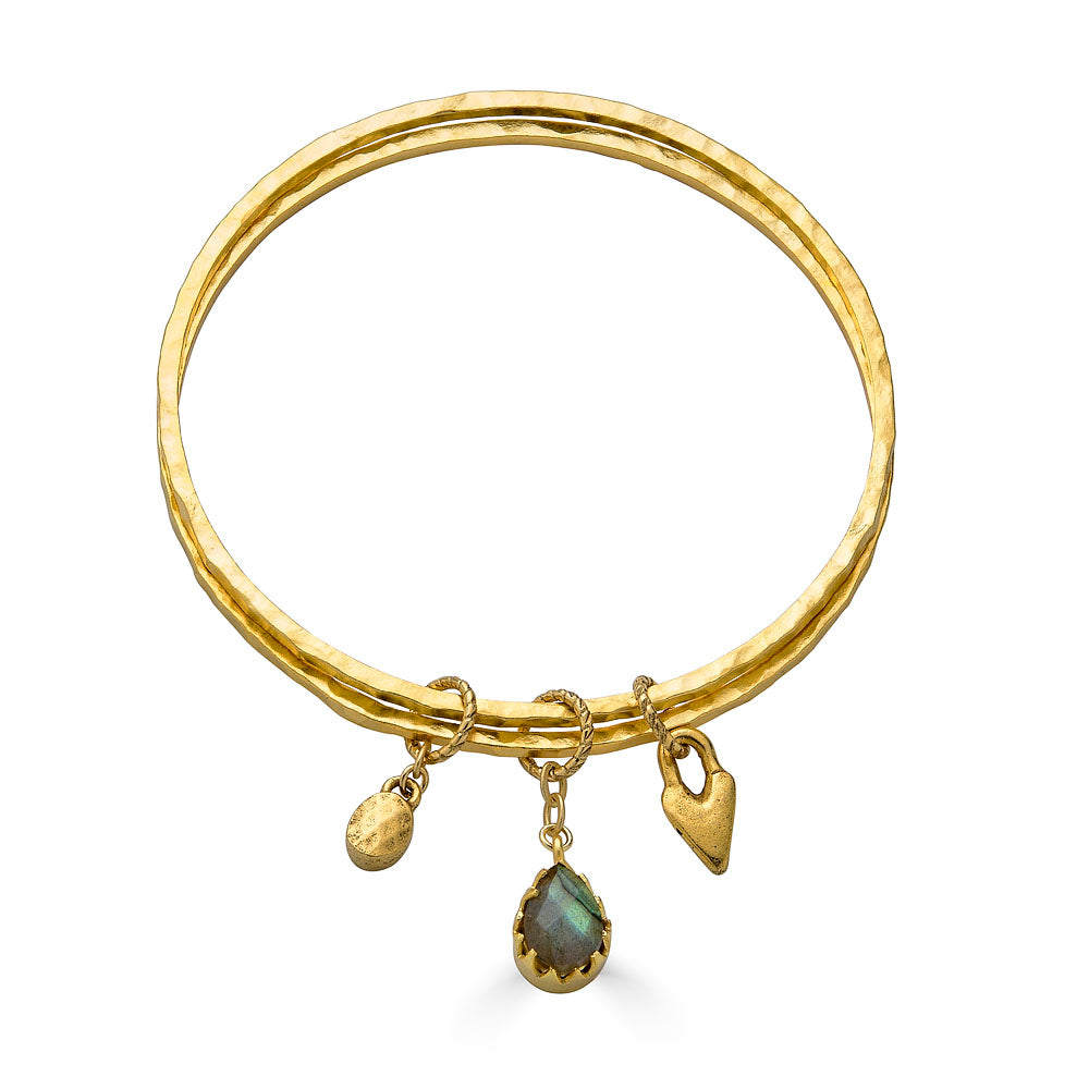 Two slim gold bangles with labradorite, heart, and gold coin charms.

