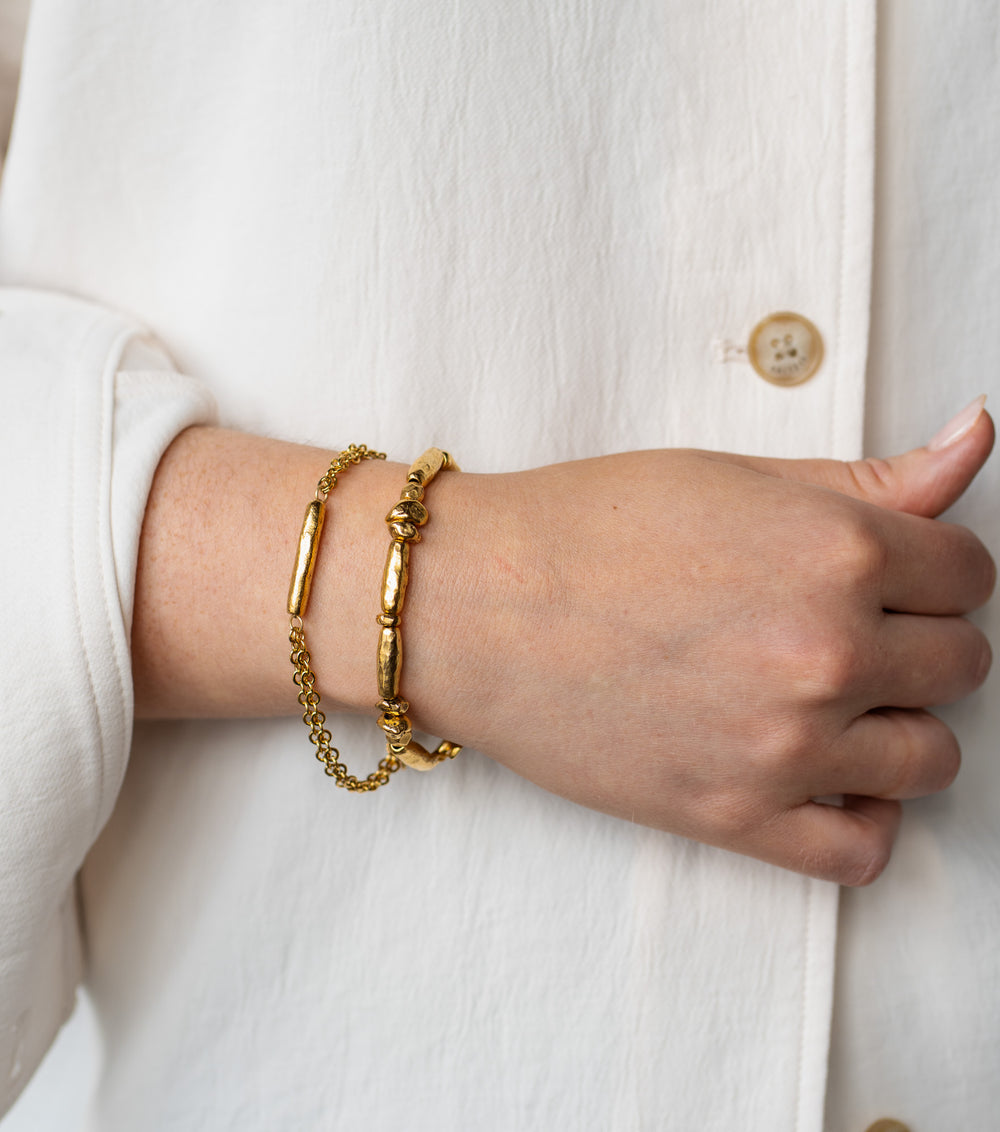 Gold bracelet with a single textured tube bead and double-strand chain.