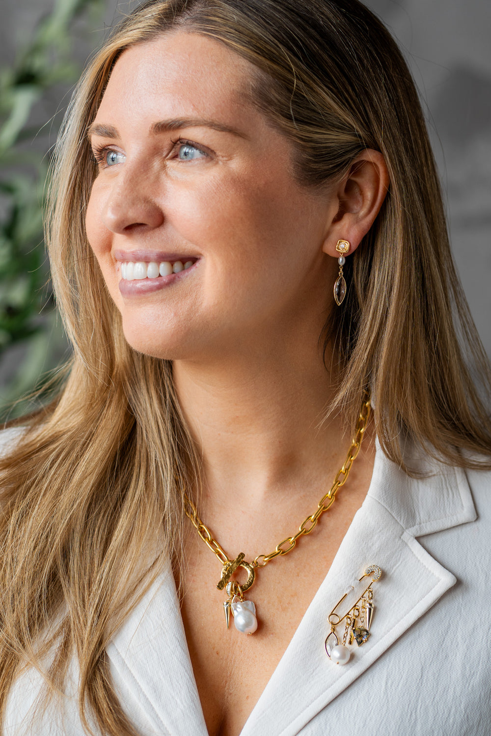 Gold necklace with marquise crystal, spike charm, and smoky gem drop on a textured clasp