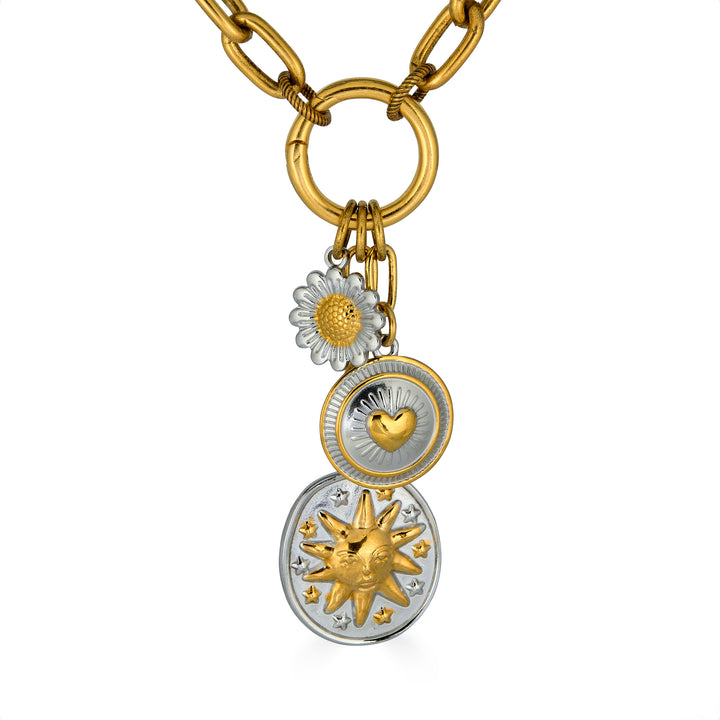 Mixed metal charm cluster necklace with sun medallion, heart charm, and daisy charm on a gold paperclip chain.