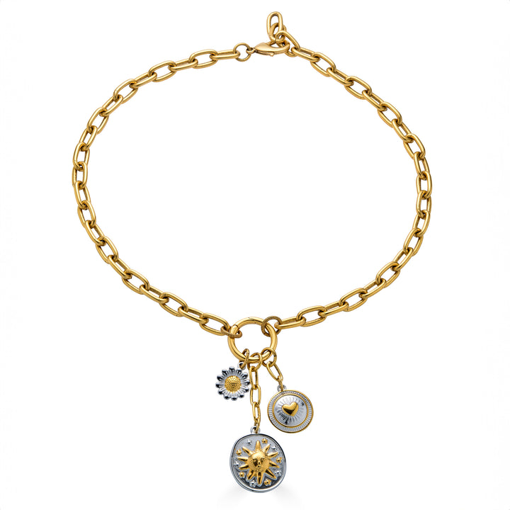 Mixed metal charm cluster necklace with sun medallion, heart charm, and daisy charm on a gold paperclip chain.