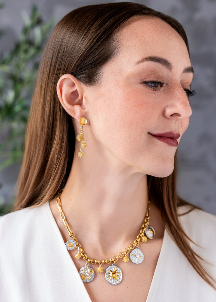 Mixed metal charm necklace with celestial, floral, heart, and ocean inspired charms hanging from a gold chain necklace.