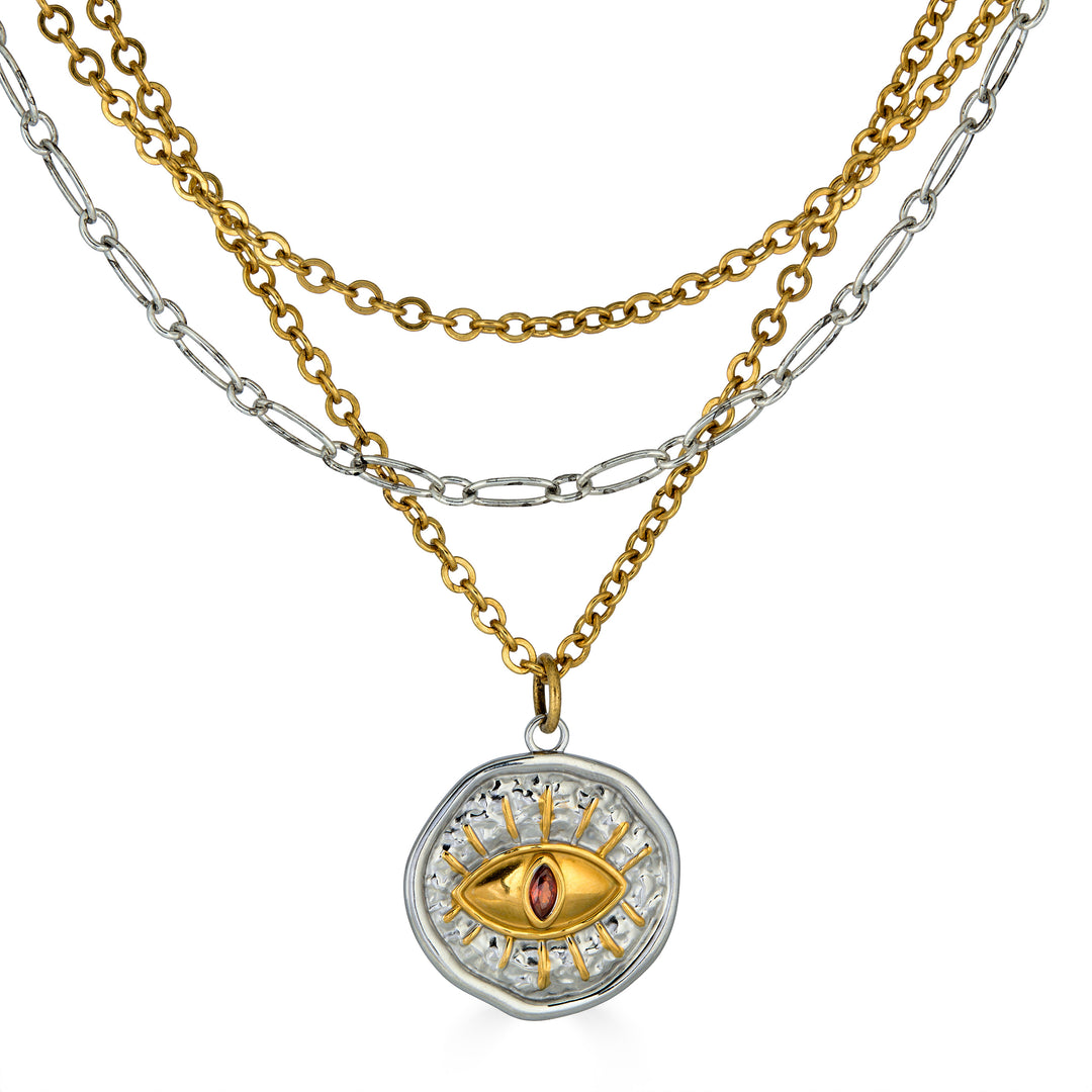 Mixed metal layered necklace with gold and silver chains and an eye pendant featuring a pink center stone.
