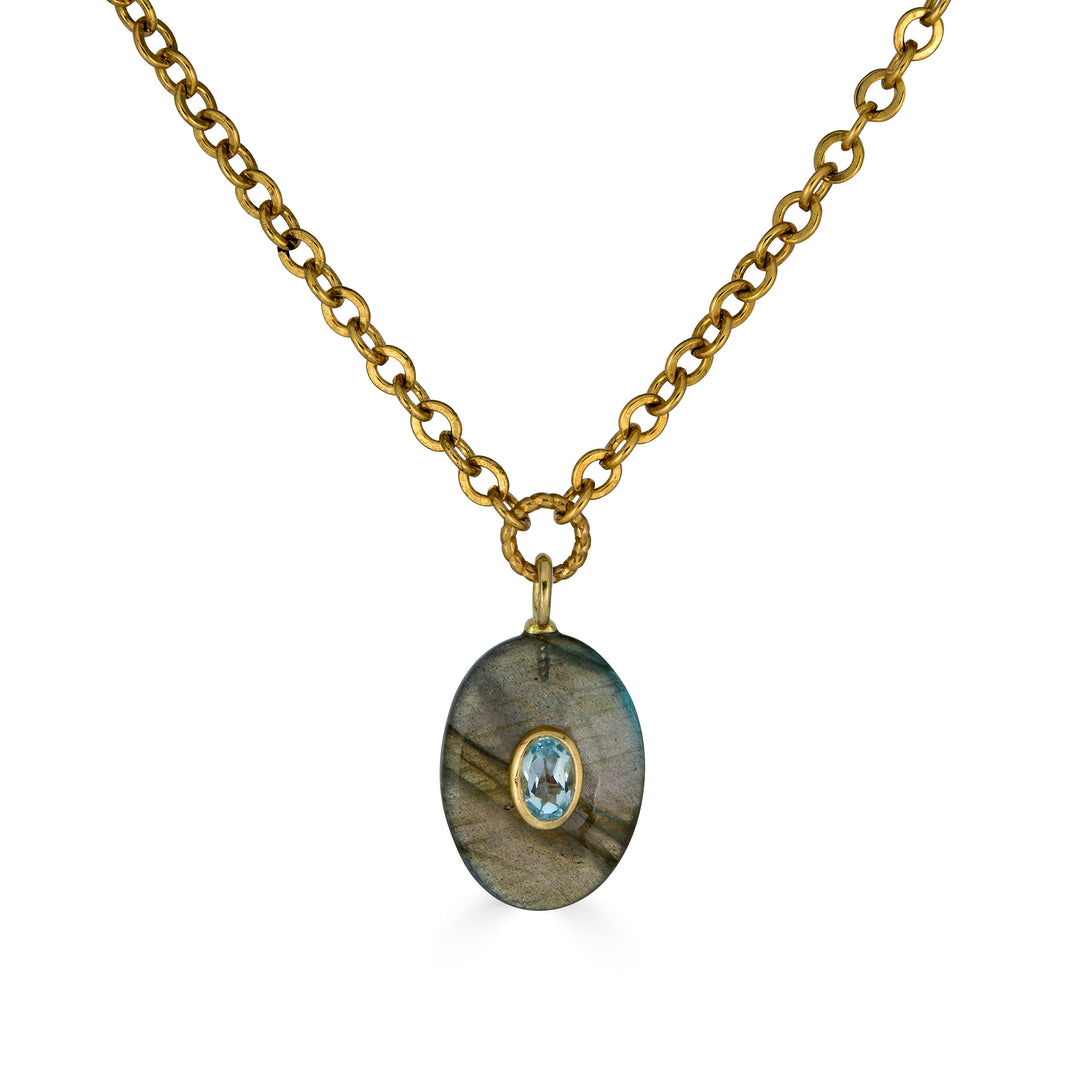Oval labradorite pendant necklace with blue topaz inlay on a gold chain.