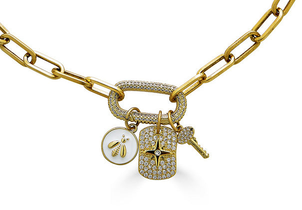 A gold paperclip chainlink necklace with a pave carabiner with white bee, pave north star, and key charms.
