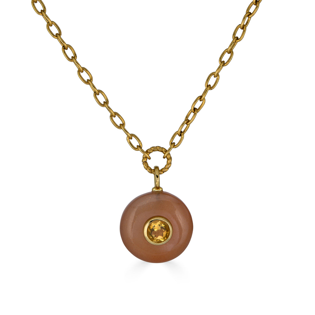 Peach moonstone pendant necklace with round citrine inlay on a gold elongated chain.