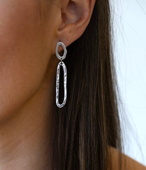 A model wearing A silver swirl dangle earring with oval cutout post.