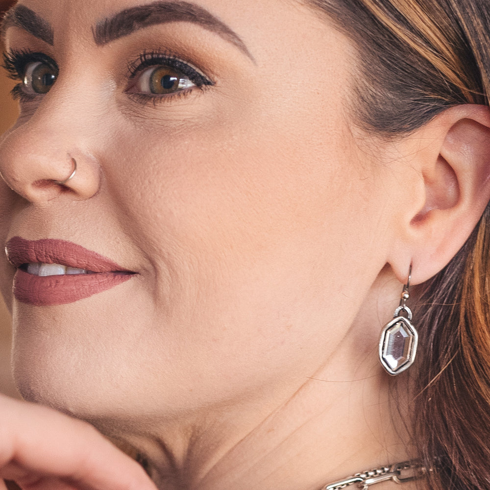 A model wearing a silver elongated hexagonal earring.
