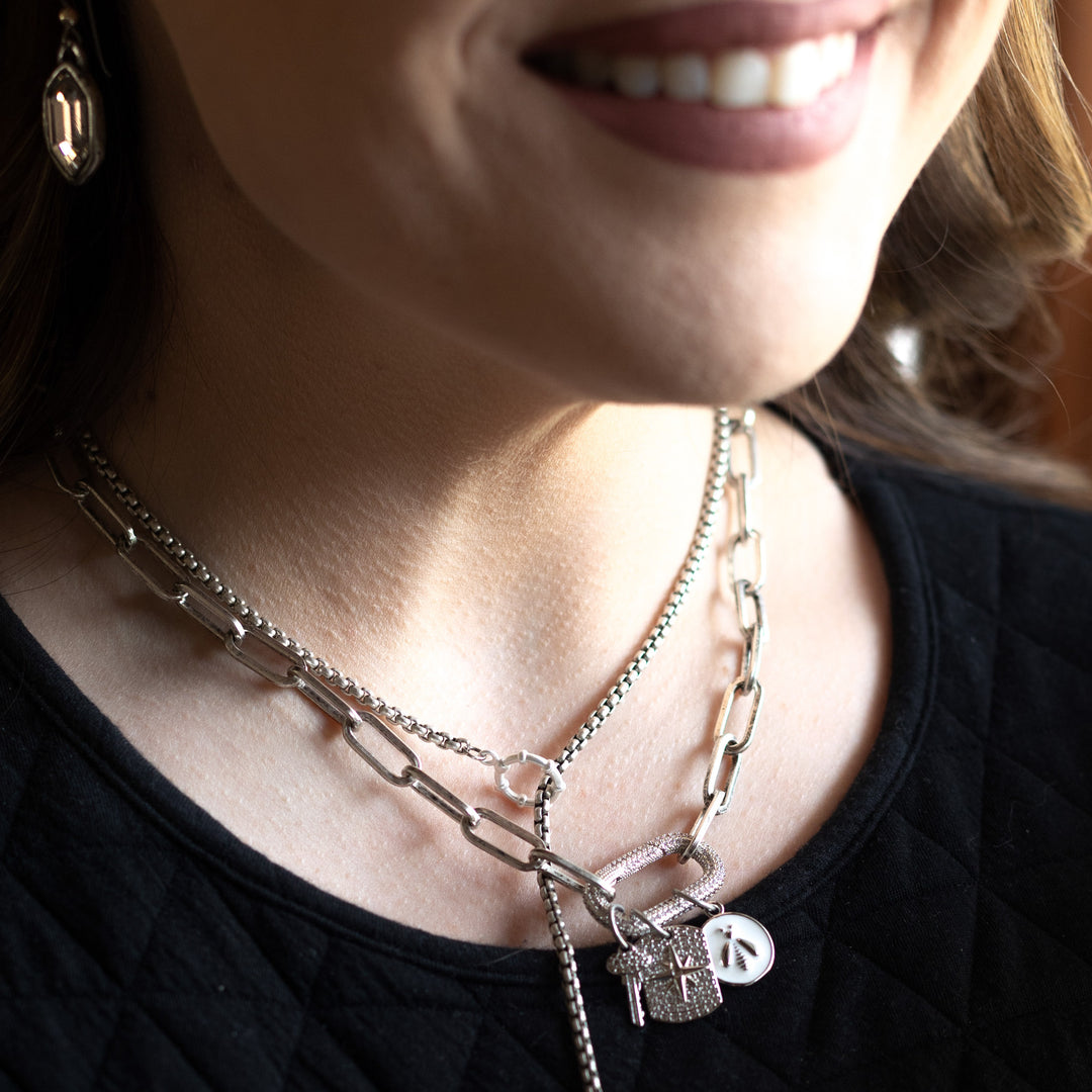A model wearing layered necklaces with silver charms.