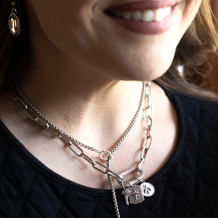 A model wearing layered chainlink charm necklaces.