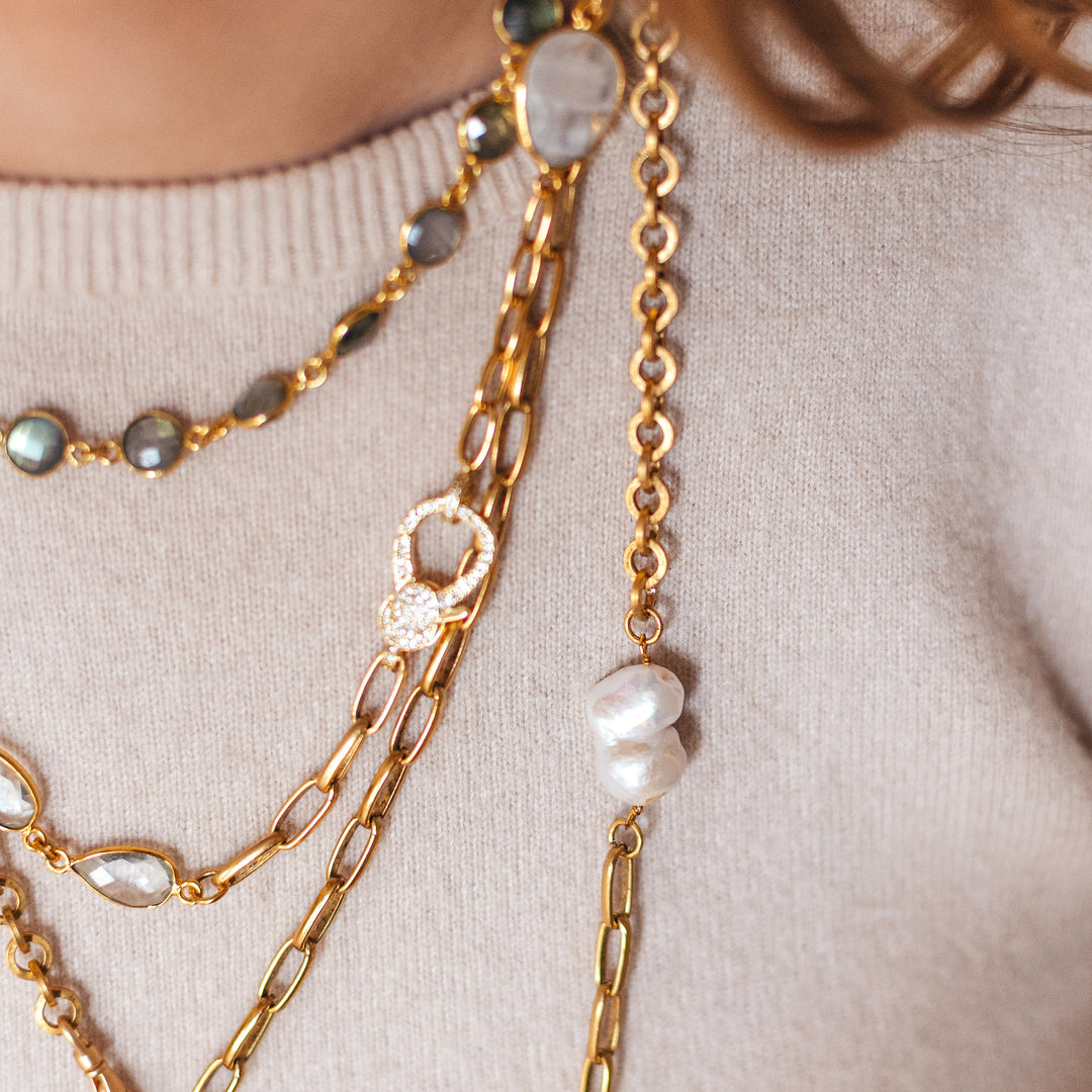 A model wearing layered chainlink and gemstone necklaces.