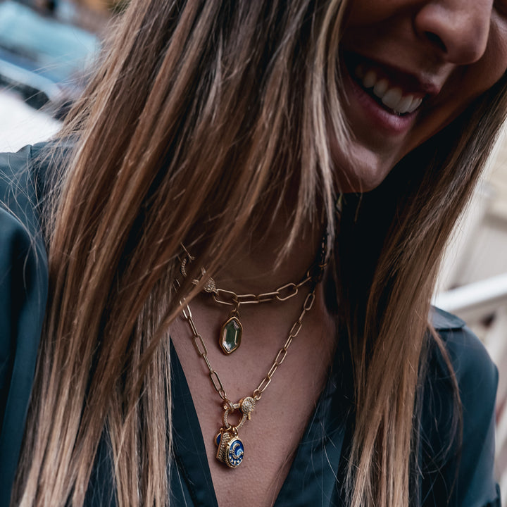 A model wearing layered paperclip chain necklaces with charm pendants.