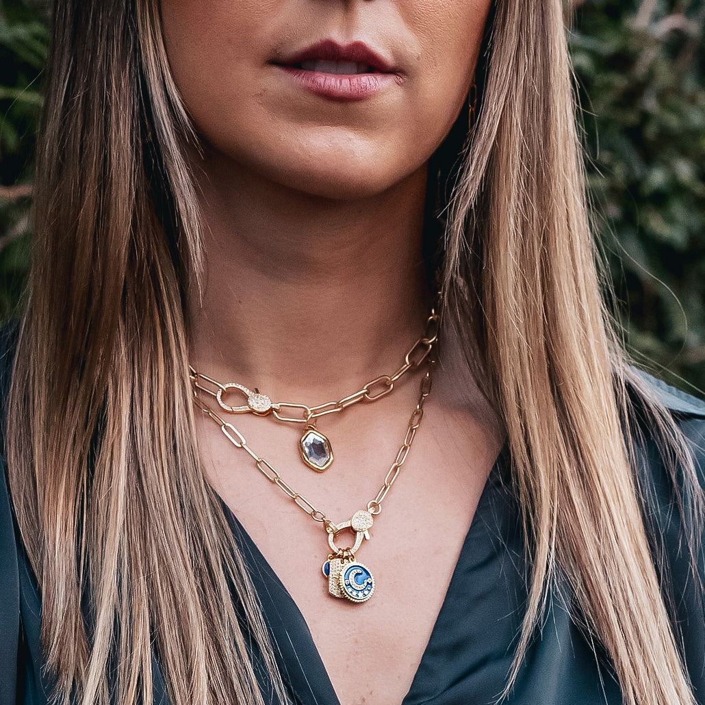 A model wearing layered paperclip chain necklaces with charm pendants.