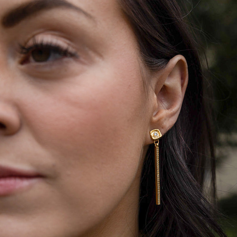 a woman wearing a crystal bar dangle earring with a crystal post