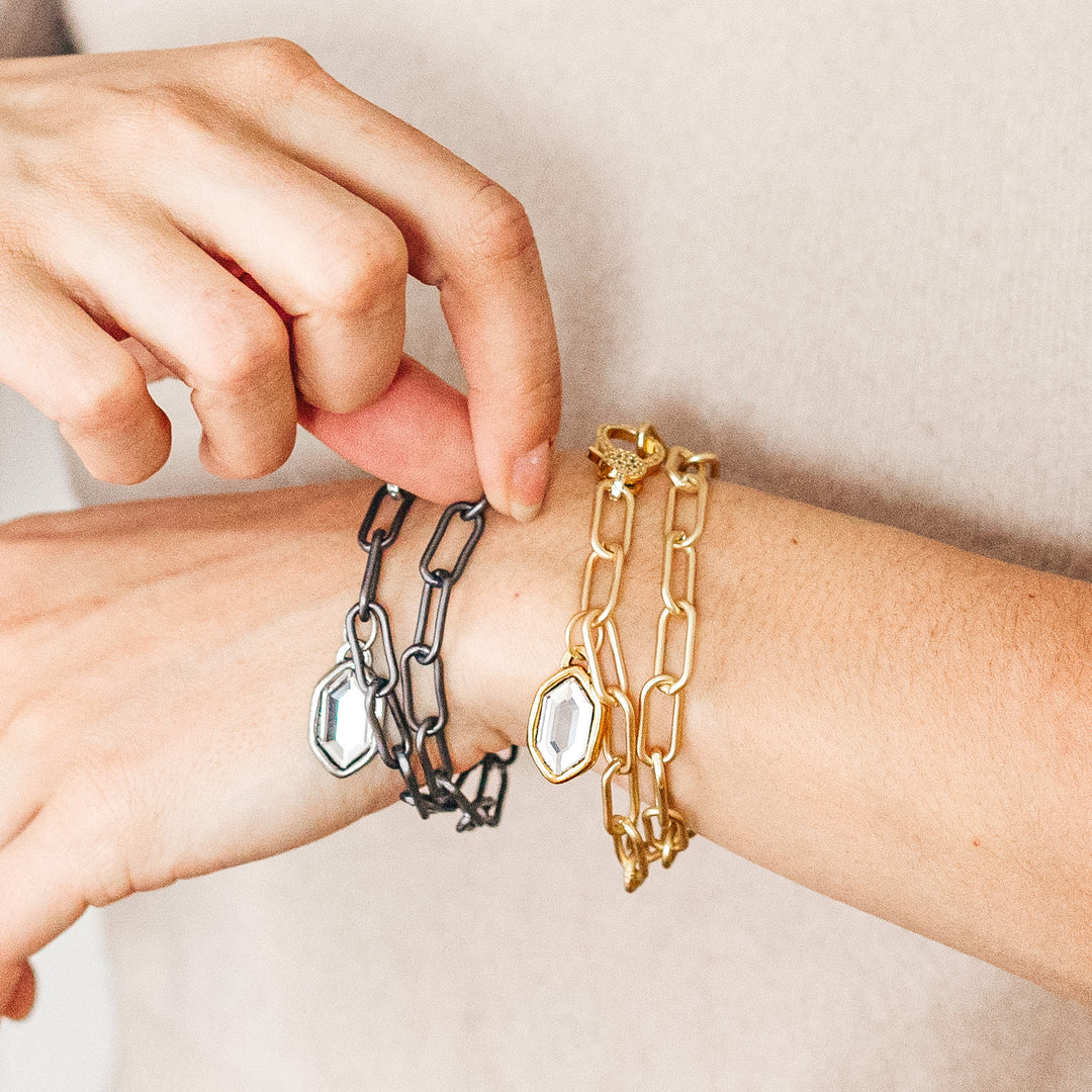 A woman's wrist modeling paperclip chainlink bracelets.