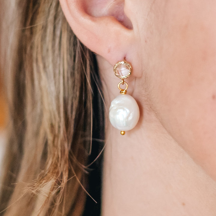 A baroque pearl earring with crystal post worn by model.