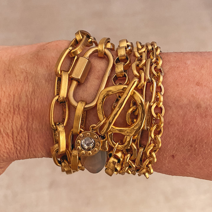 A woman's wrist modeling gold chainlink bracelets.