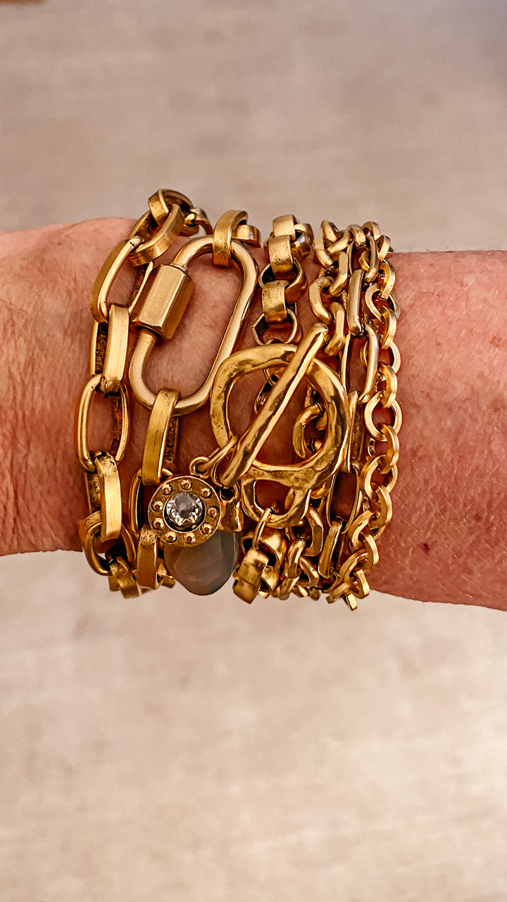 A woman's wrist modeling gold chainlink bracelets.