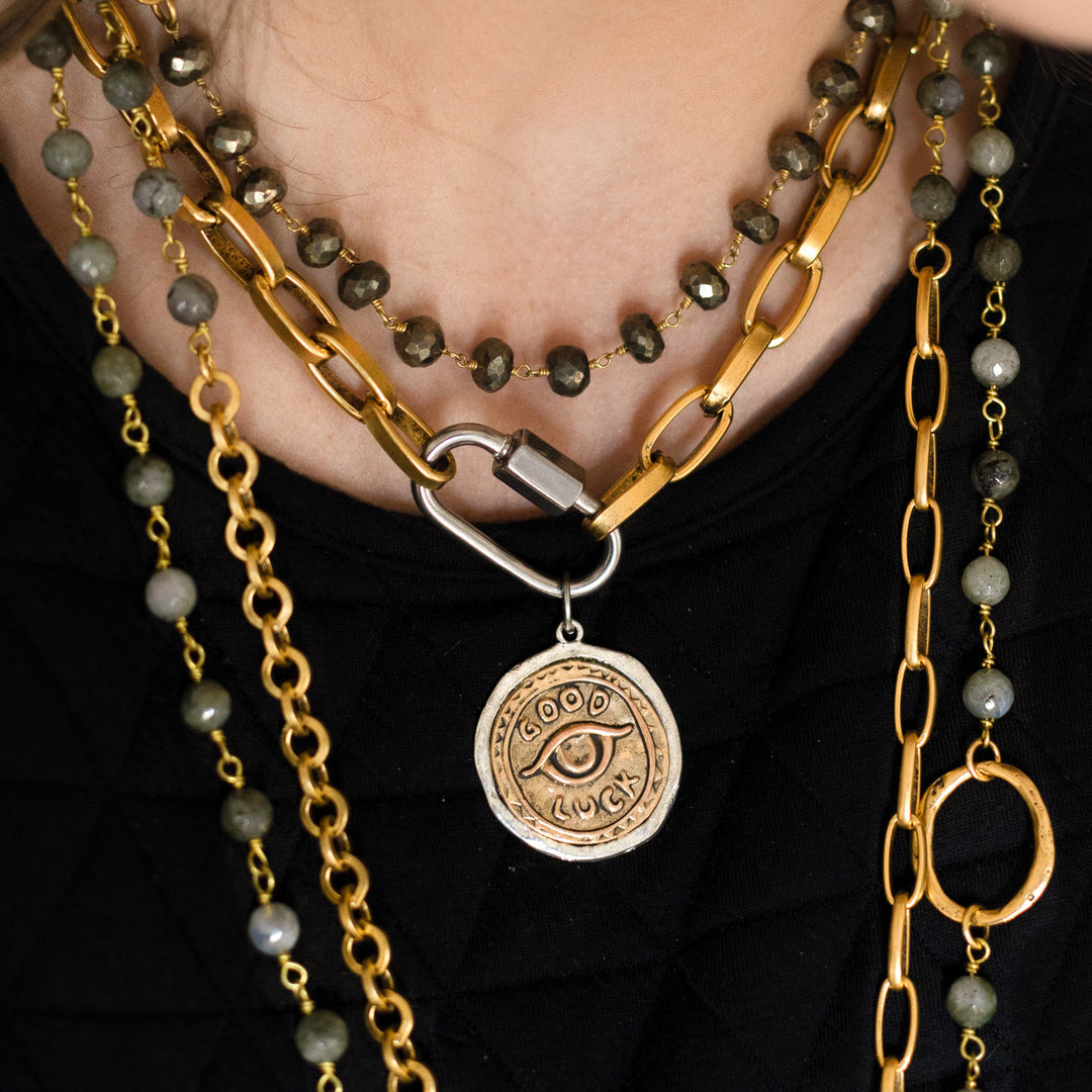 A model wearing layered chainlink and gemstone necklaces.