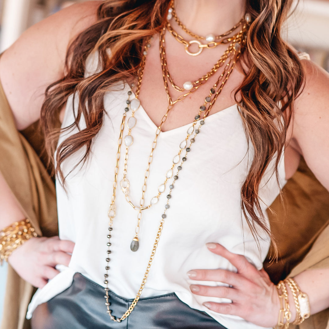 A model wearing layered chainlink and gemstone necklaces.