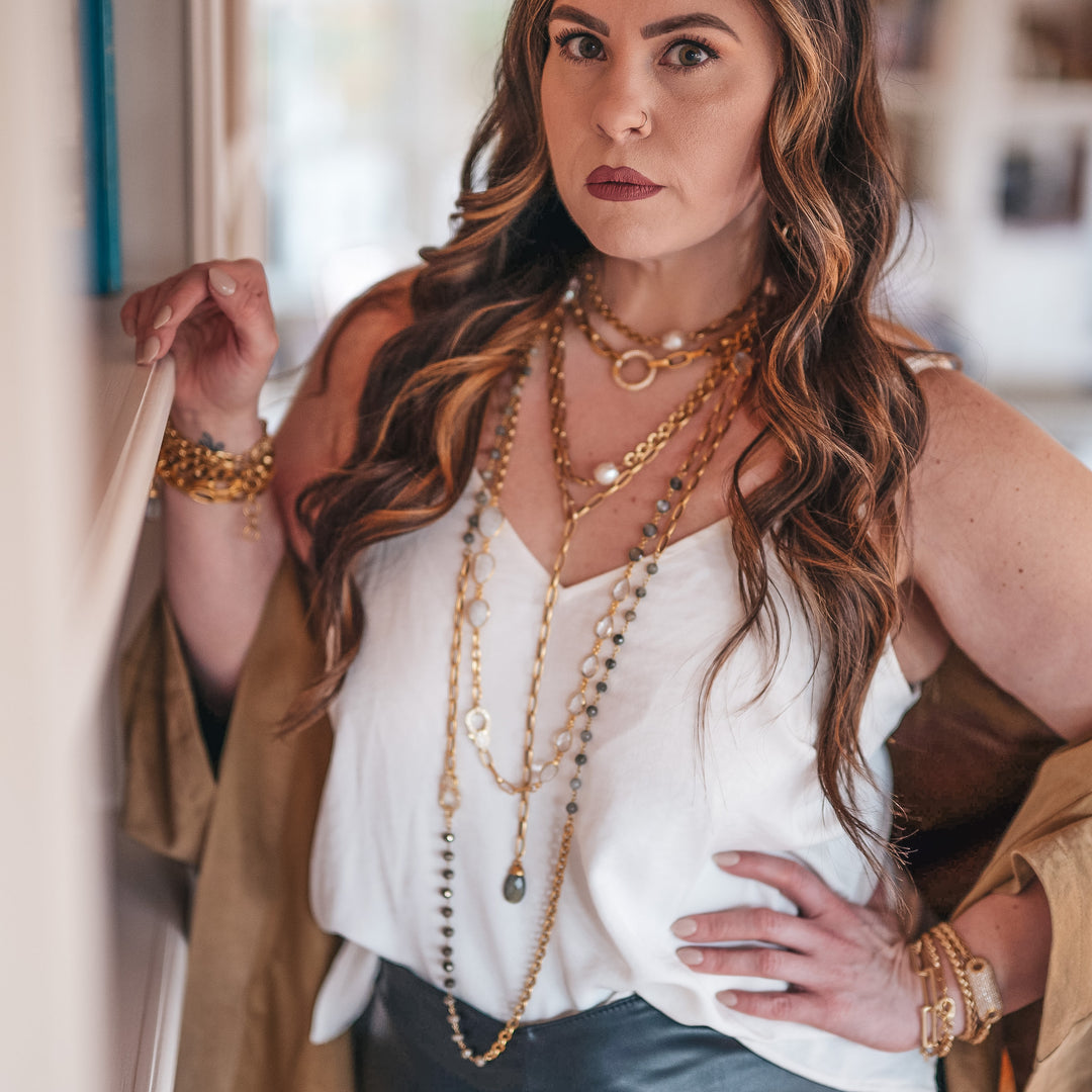 A model wearing layered chainlink and gemstone necklaces.