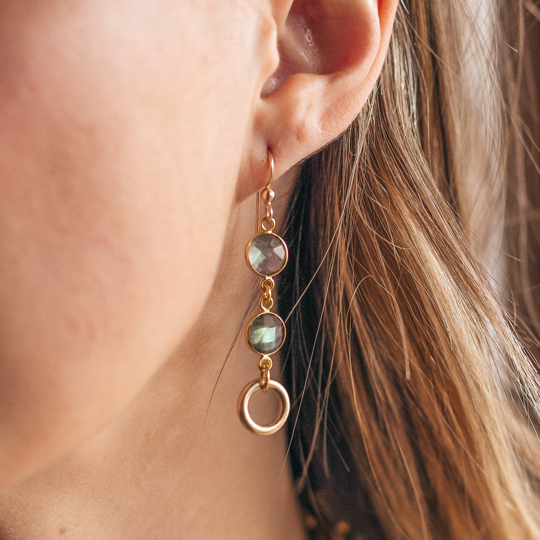 A gold labradorite earring with circle detail worn by model.