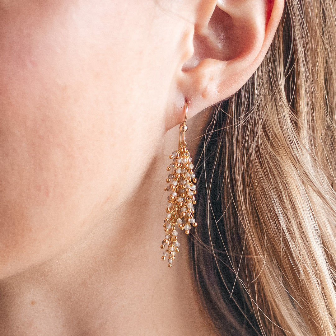 A model wearing a gold labradorite drizzle earring.