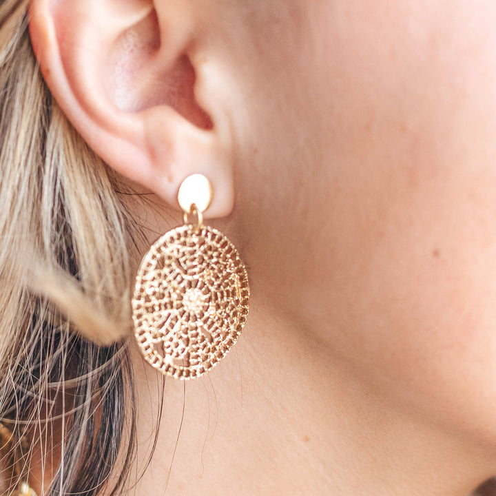 A model wearing a round gold lace earring.
