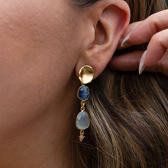 a pair of earring with bezel set kyanite and aquamarine stones on a lotus leaf post