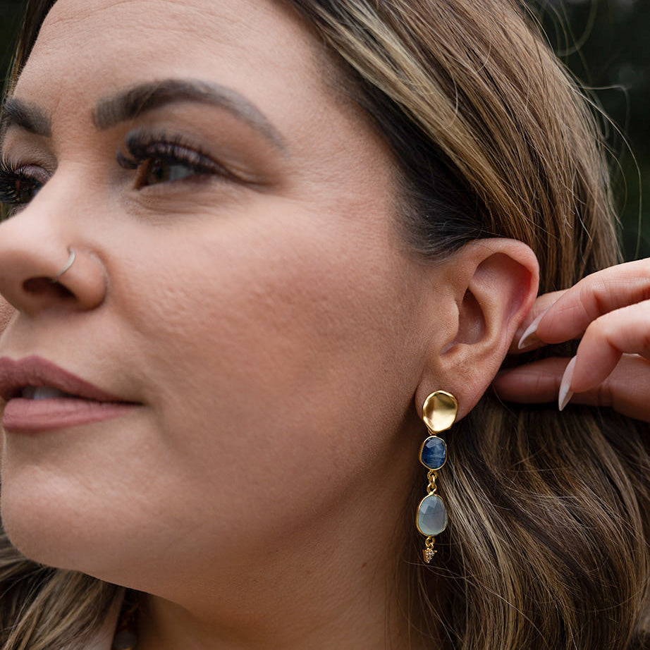 a pair of earring with bezel set kyanite and aquamarine stones on a lotus leaf post