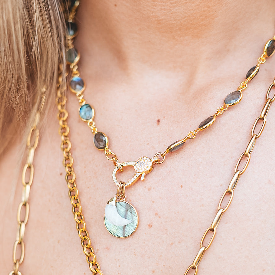 a model wearing a labradorite necklace with a heart shaped labradorite pendant and a moonstone moon with a pave clasp