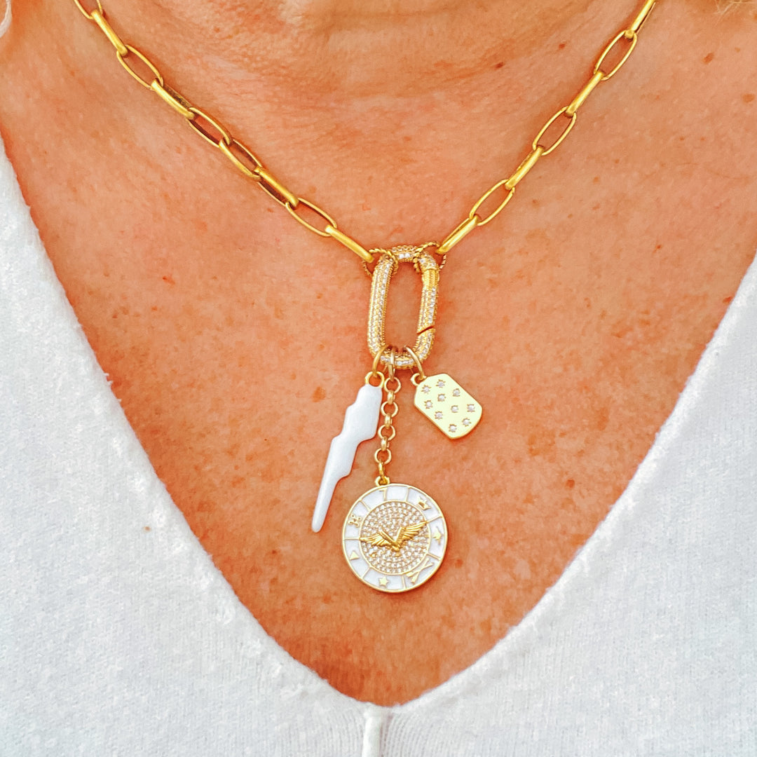 A model wearing a gold paperclip chainlink necklace with white lightning, wing wheel, and star charms on a pave spring clasp.