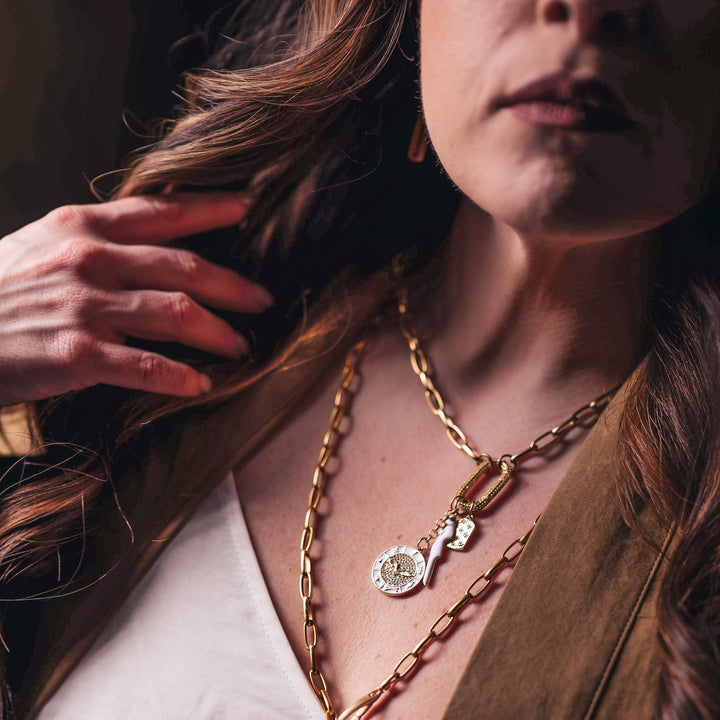 A model wearing layered gold chainlink necklaces with charms.
