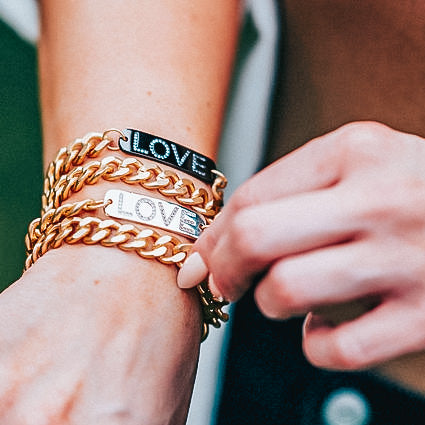 A woman's wrist modeling chainlink CZS LOVE bracelets.