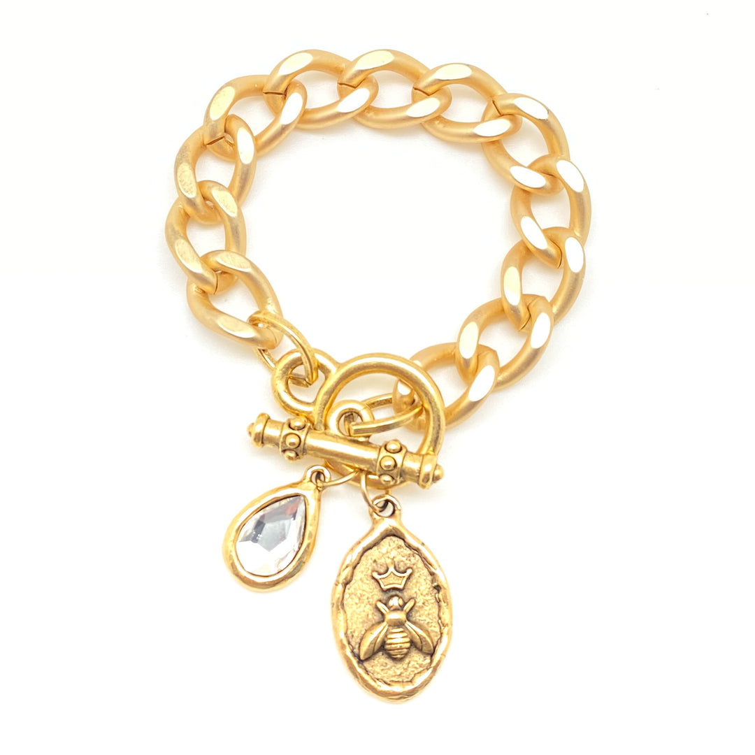 A matte gold chunky curb chain bracelet with oval bee and crystal charms.