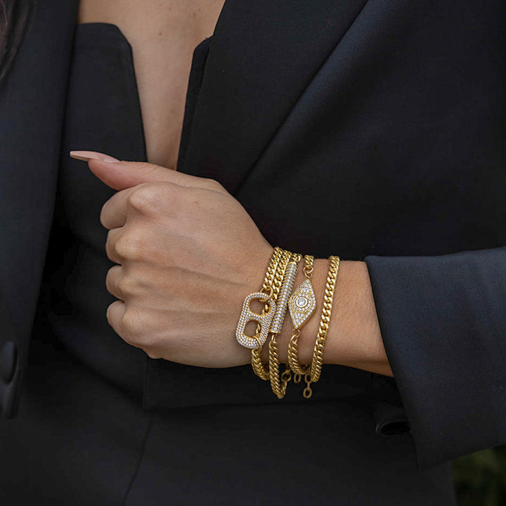 a matte gold pave bracelet stack with evil eye, can tab and pave bar details.