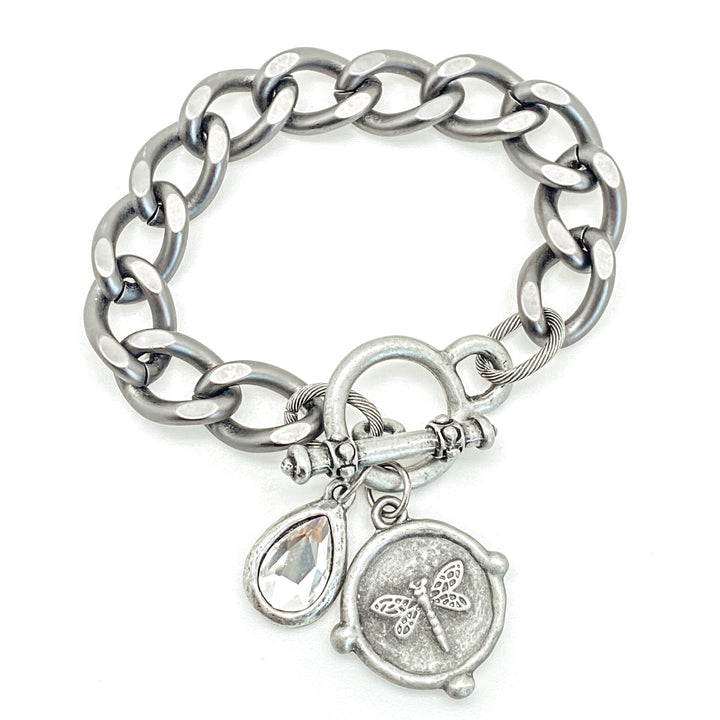 A silver chunky curb chain bracelet with round dragonfly and crystal charms.