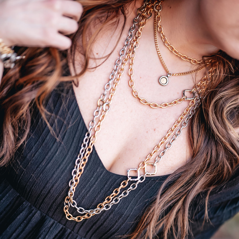 A model wearing layered gold and silver chainlink necklaces.