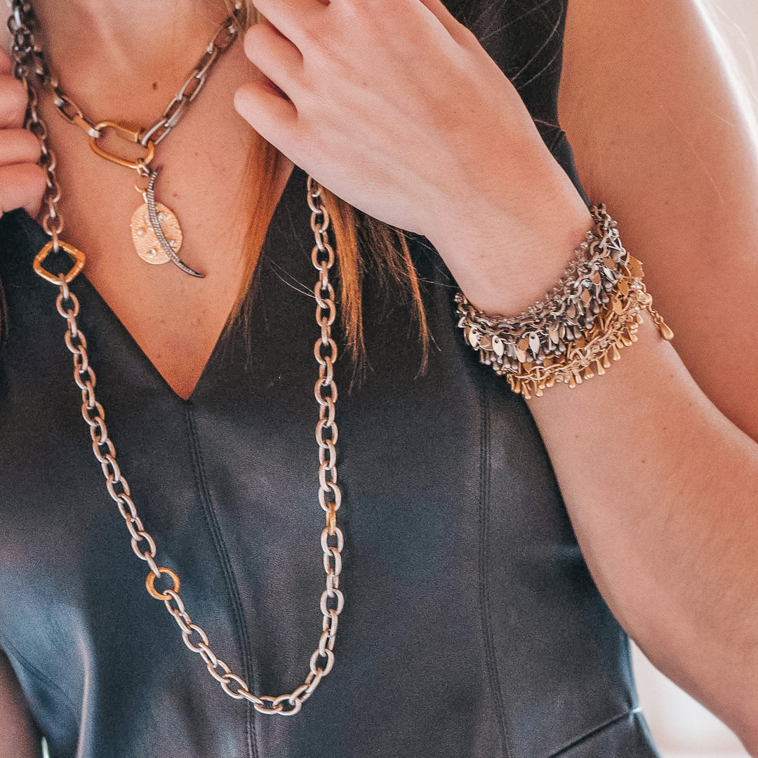 A model wearing layered chainlink necklaces and bracelets.