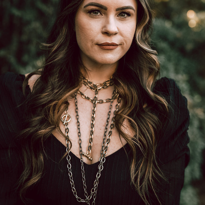 A woman modeling layered chainlink necklaces.