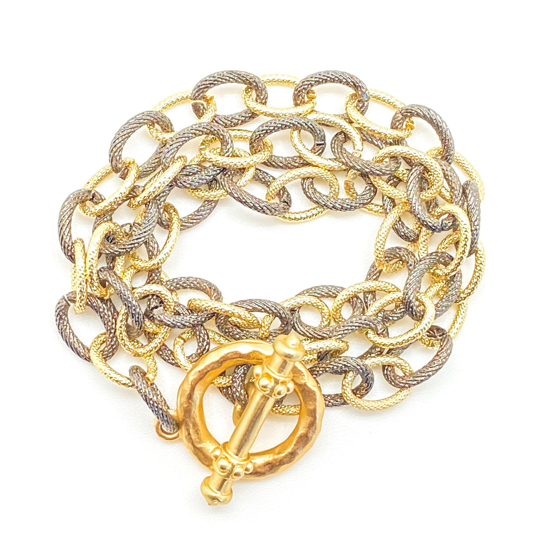 A triple wrap rhodium chain bracelet-necklace with textured circle chains.