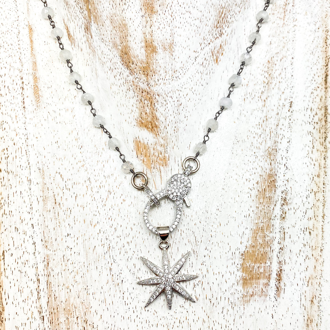 A moonstone gemstone necklace with pave clasp and star pendant.