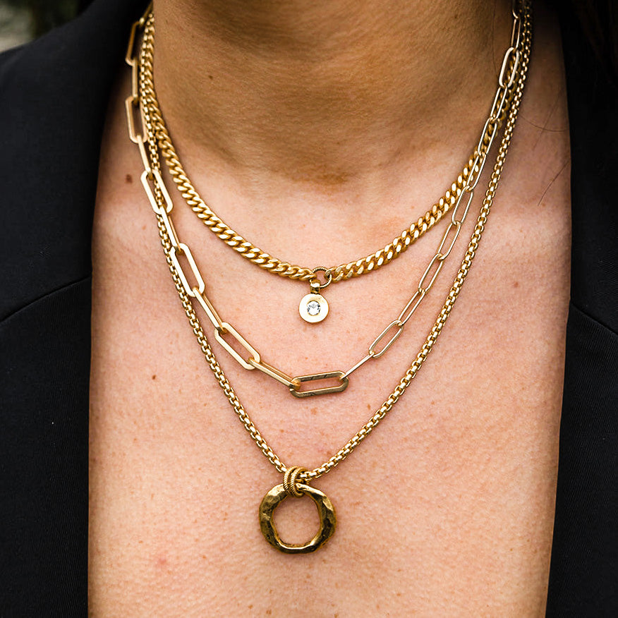 a necklace stack with three matte gold necklaces with round pendants 