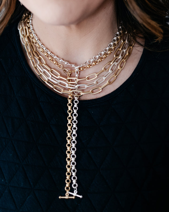 A model wearing layered gold and silver chainlink necklaces.
