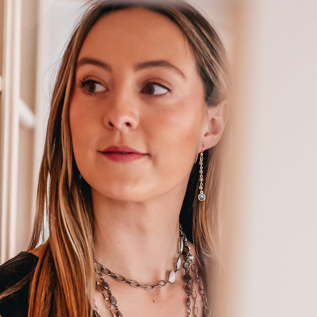 A model wearing a labradorite and blue crystal drop earring.