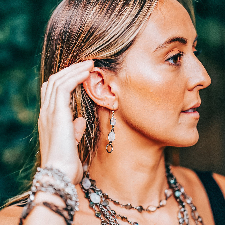 A model wearing a silver moonstone drop earring.